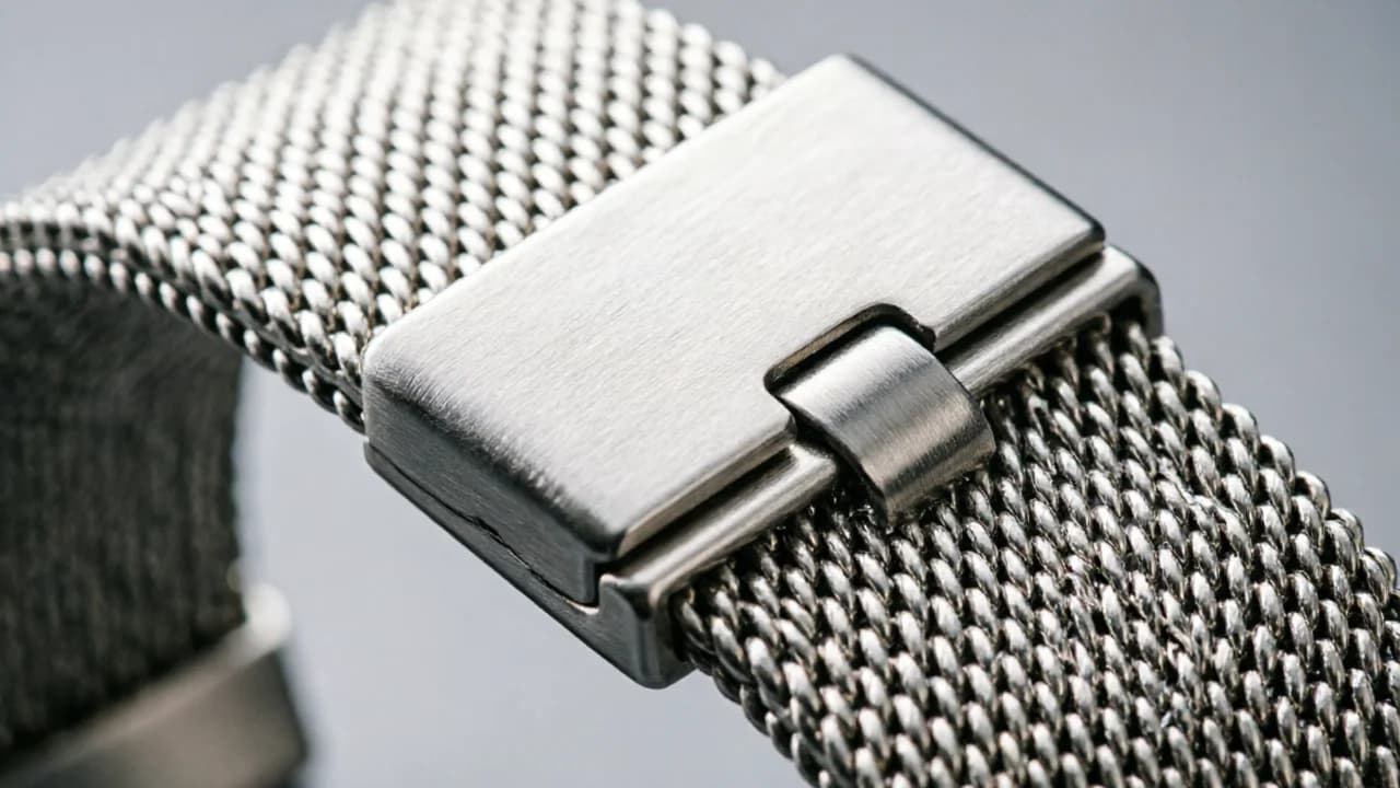 Macro close-up of a stainless steel watch clasp and mesh strap